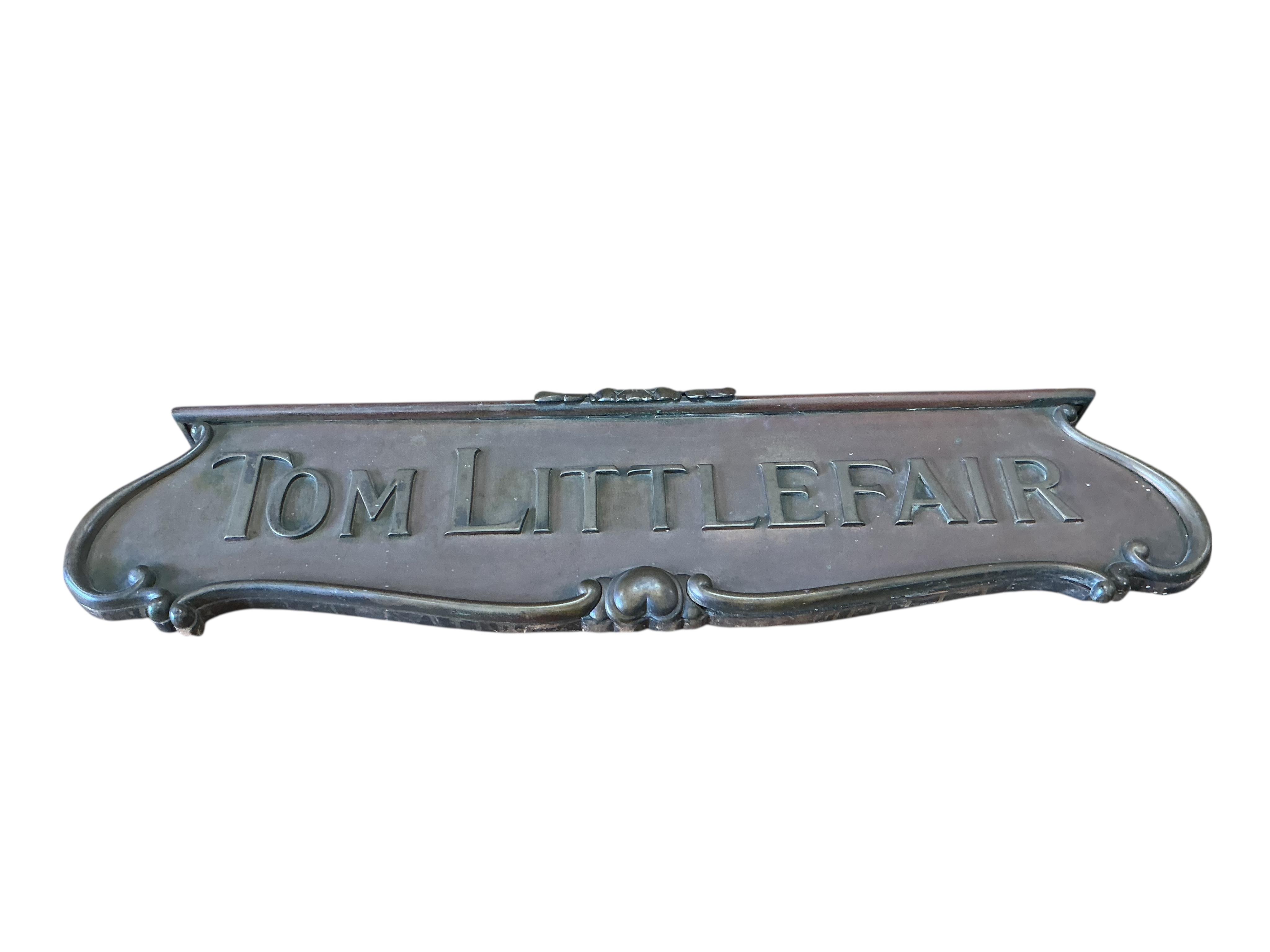 A cast brass 'Tom Littlefair' shop sign, width 104cm, height 27cm